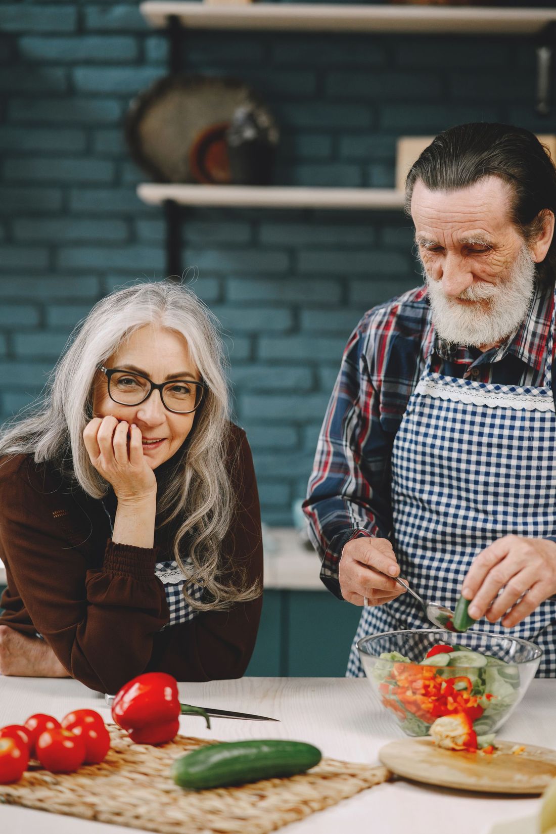 Older couple preparing a salad together at a kitchen counter