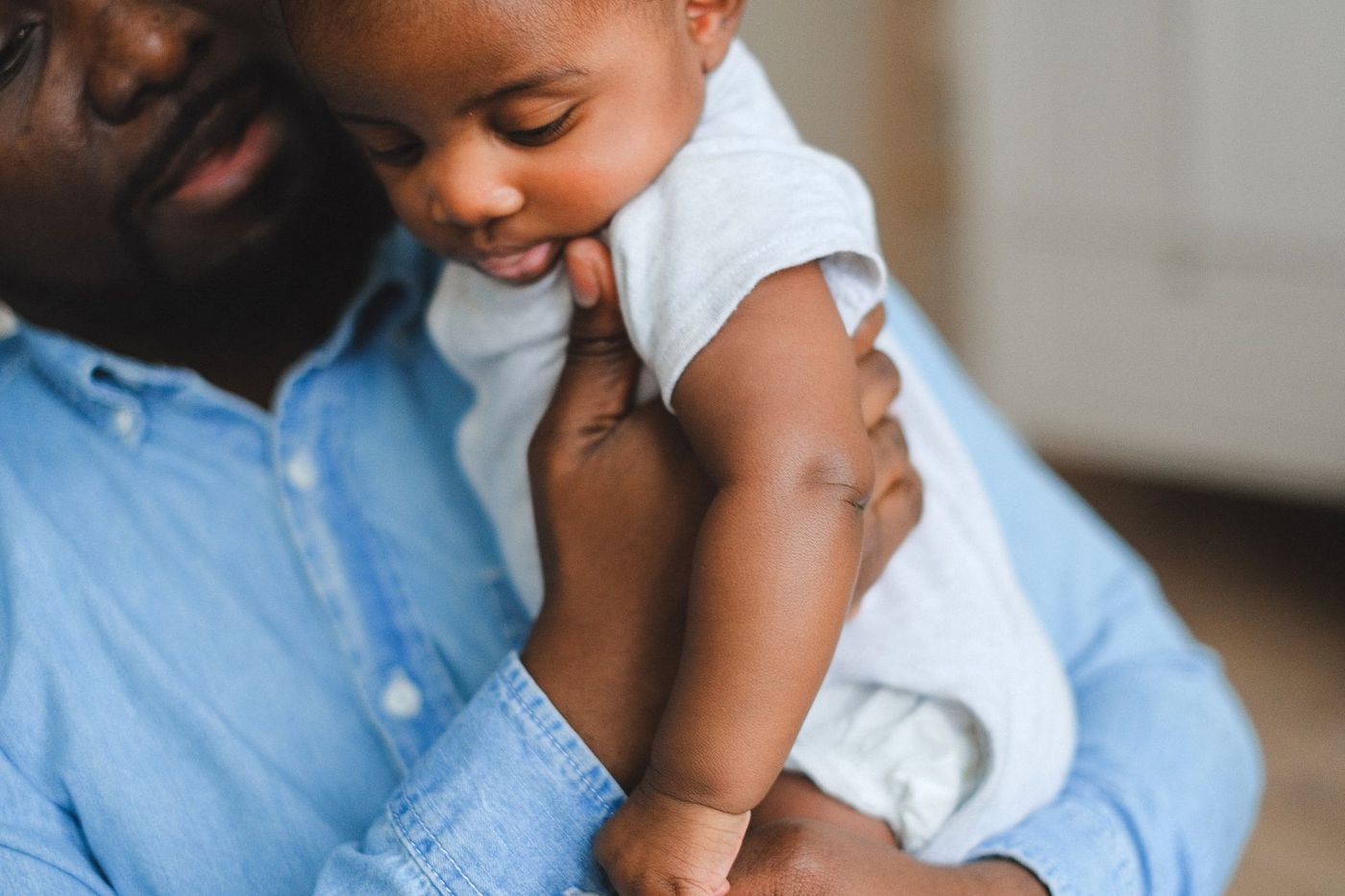 Man holding a baby against his shoulder in a home interior